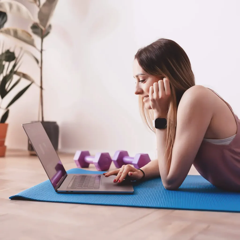 ragazza su tappetino fitness e pesi con PC