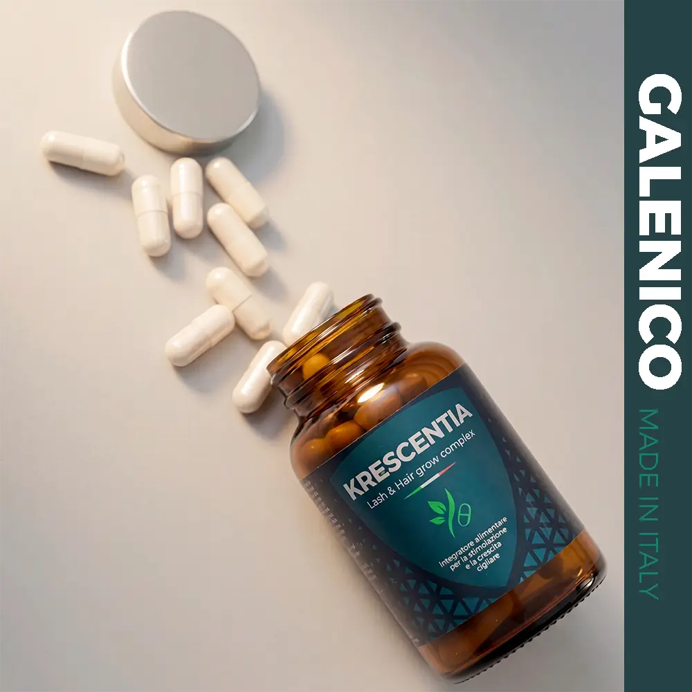flacone vetro ambrato sdraiato su tavolo da cui escono capsule integratore